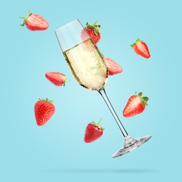 Image of Sparkling wine in glass and fresh strawberries falling against light blue background