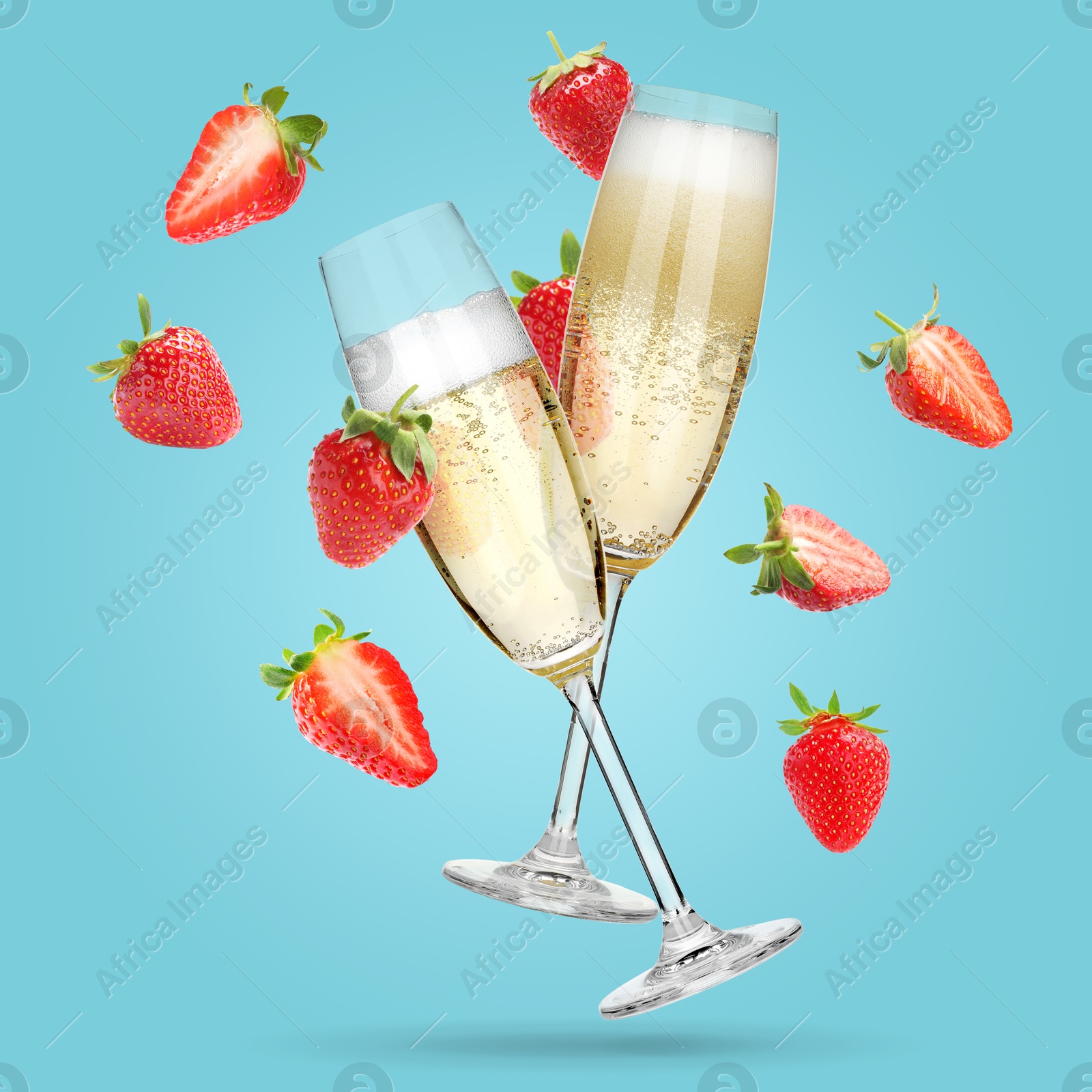 Image of Sparkling wine in flute glasses and fresh strawberries falling against light blue background