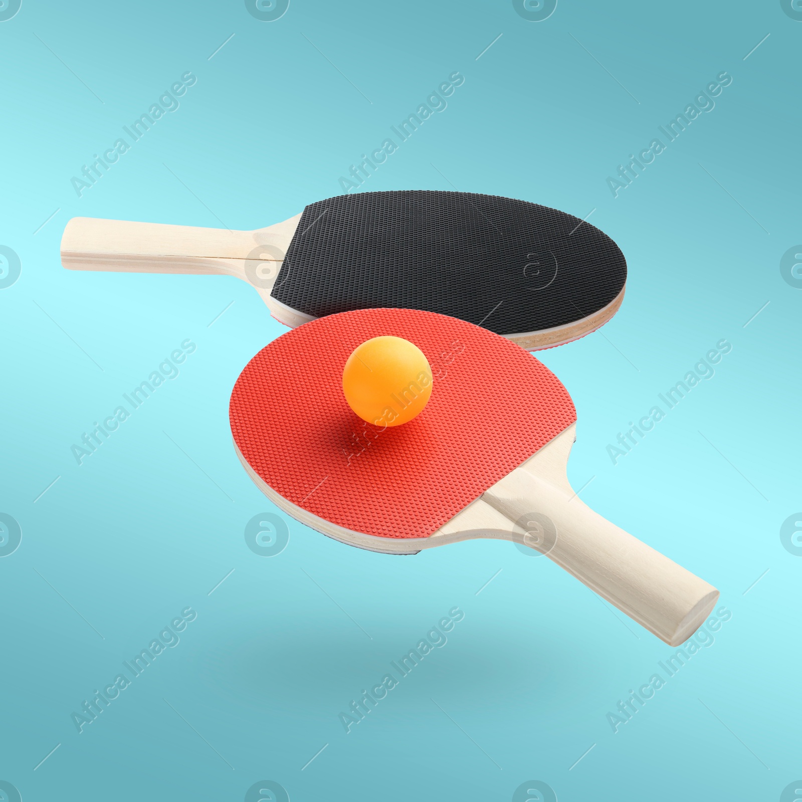 Ping pong rackets and ball in air against light blue background Image of Ping pong rackets and ball in air against light blue background