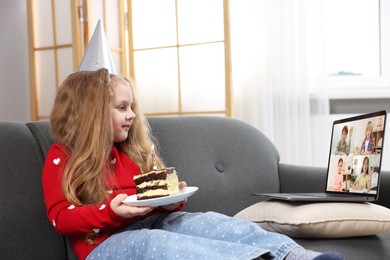 Image of Celebrating birthday online. Little girl with cake having video call with friends via laptop at home