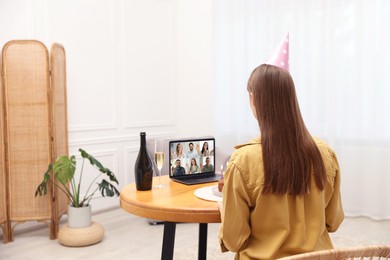 Image of Celebrating birthday online. Woman having video call with friends via laptop at home