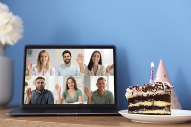 Image of Celebrating birthday online. Video call with friends via laptop, cake and party hat on table indoors