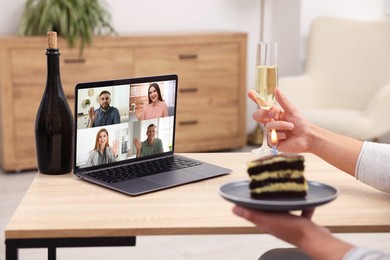 Image of Celebrating birthday online. Man with sparkling wine and cake having video call with friends via laptop at home, closeup