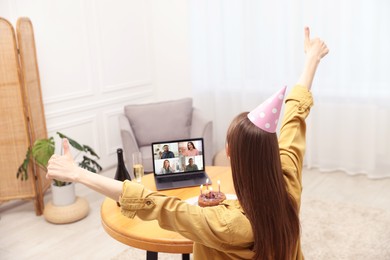 Image of Celebrating birthday online. Woman having video call with friends via laptop at home