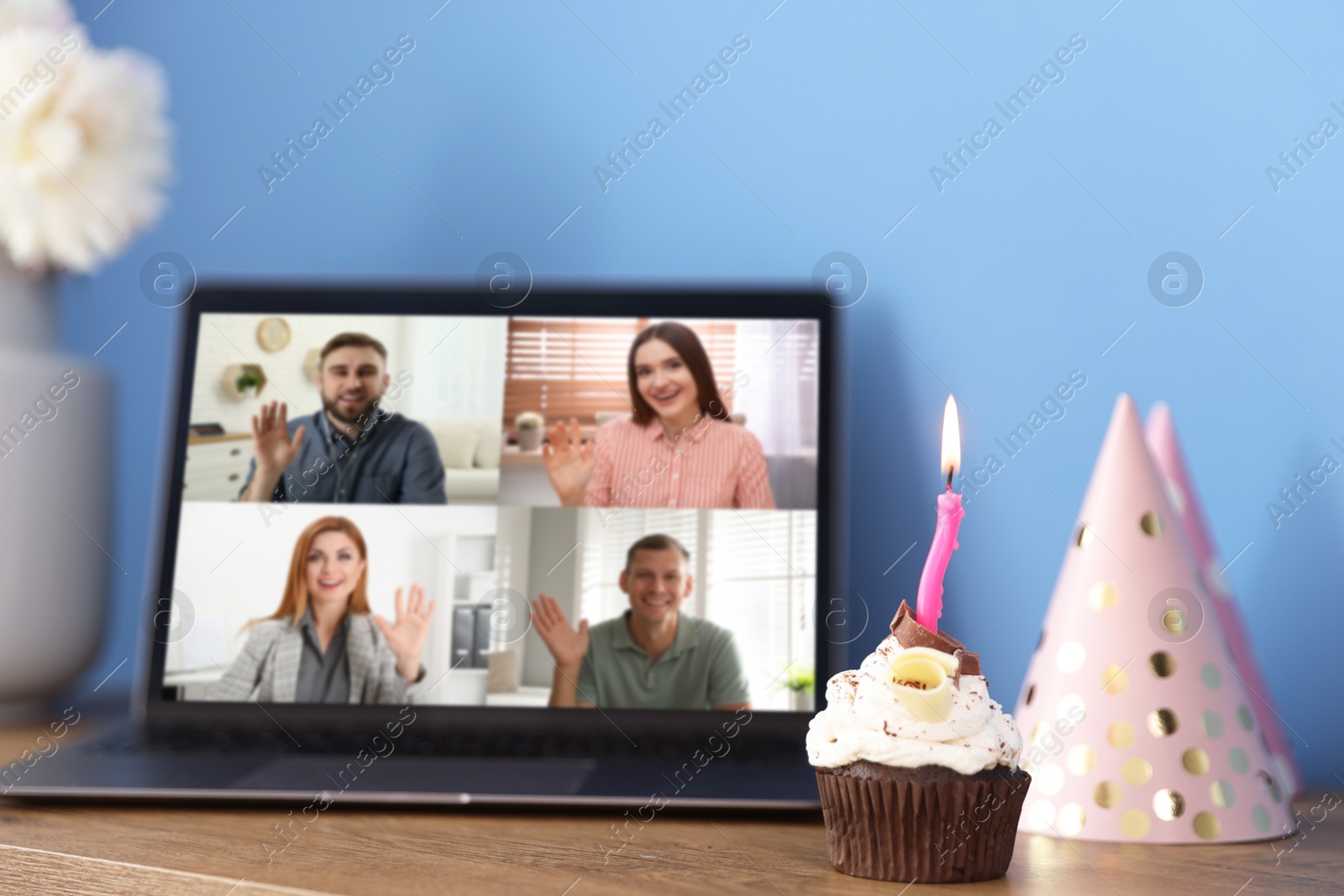 Celebrating birthday online. Video call with friends via laptop, cupcake and party hat on table indoors Image of Celebrating birthday online. Video call with friends via laptop, cupcake and party hat on table indoors