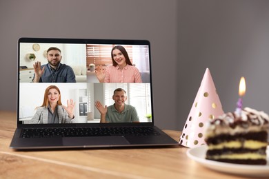 Image of Celebrating birthday online. Video call with friends via laptop, cake and party hat on table indoors