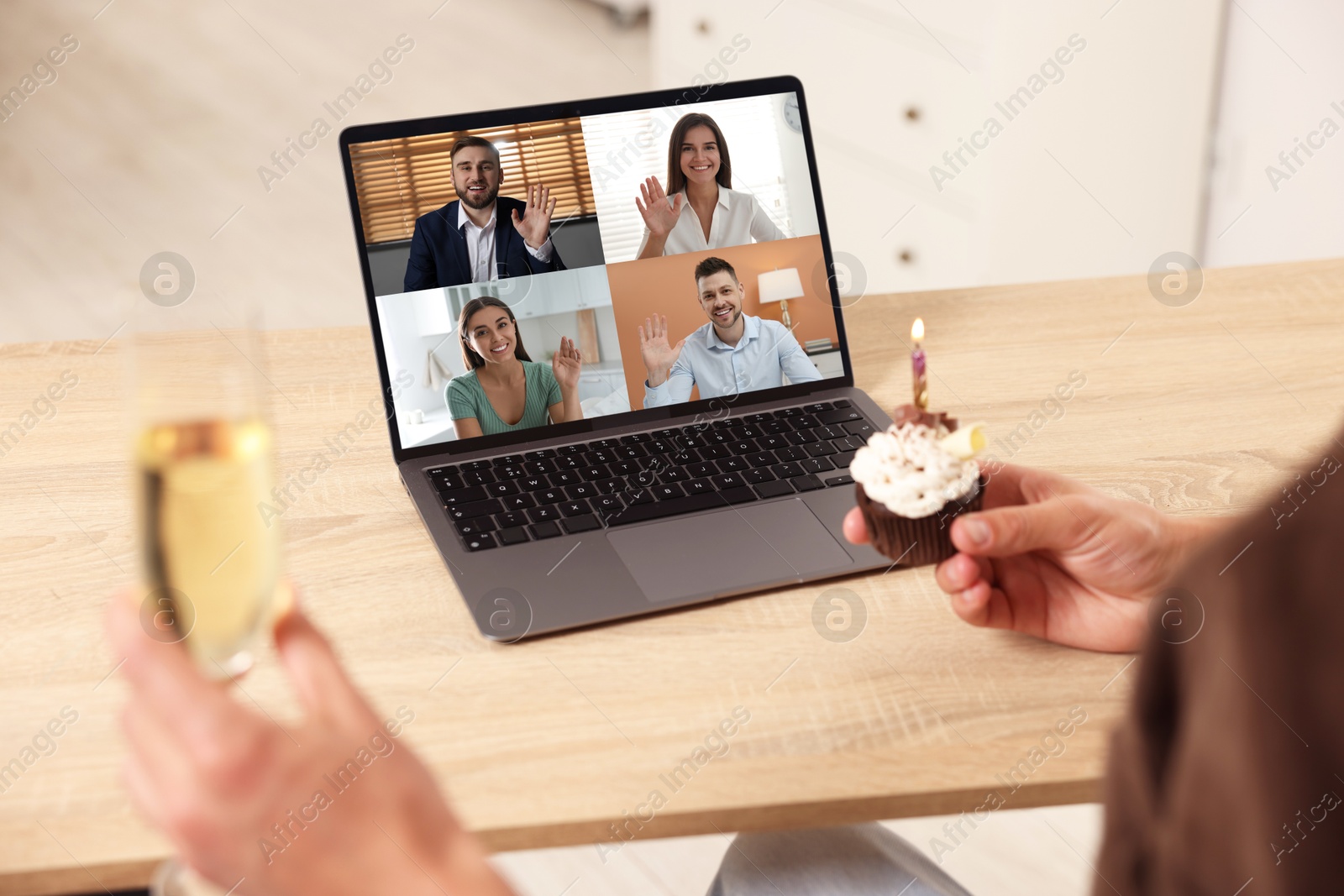 Celebrating birthday online. Man with sparkling wine and cupcake having video call with friends via laptop at home, closeup Image of Celebrating birthday online. Man with sparkling wine and cupcake having video call with friends via laptop at home, closeup