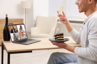 Image of Celebrating birthday online. Man with sparkling wine and cake having video call with friends via laptop at home, closeup