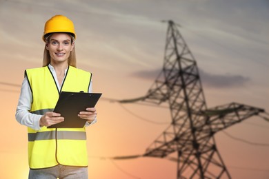 Image of Power engineer in hard hat holding clipboard against high voltage tower