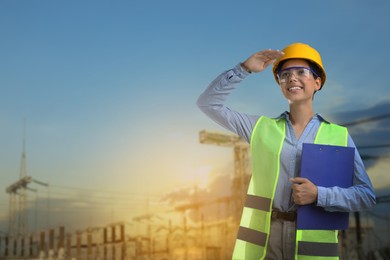 Image of Power engineer in hard hat holding clipboard against electrical substation