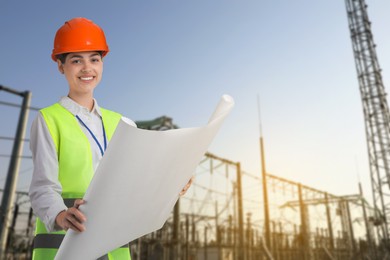 Image of Power engineer in hard hat holding draft against electrical substation