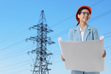 Image of Power engineer in hard hat holding draft against high voltage tower