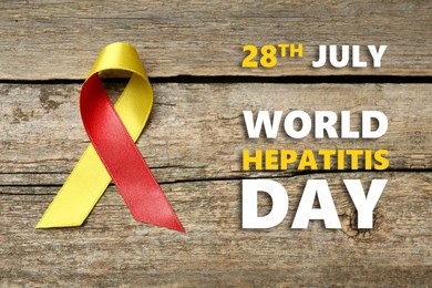 Image of 28th july World Hepatitis Day. Yellow-red awareness ribbon on wooden background, top view