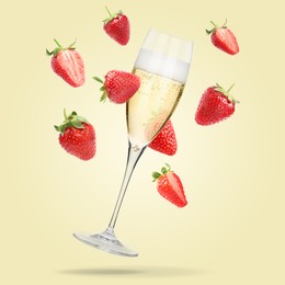 Image of Sparkling wine in glass and fresh strawberries falling against beige background
