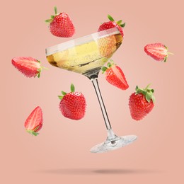 Image of Sparkling wine in glass and fresh strawberries falling against pink background
