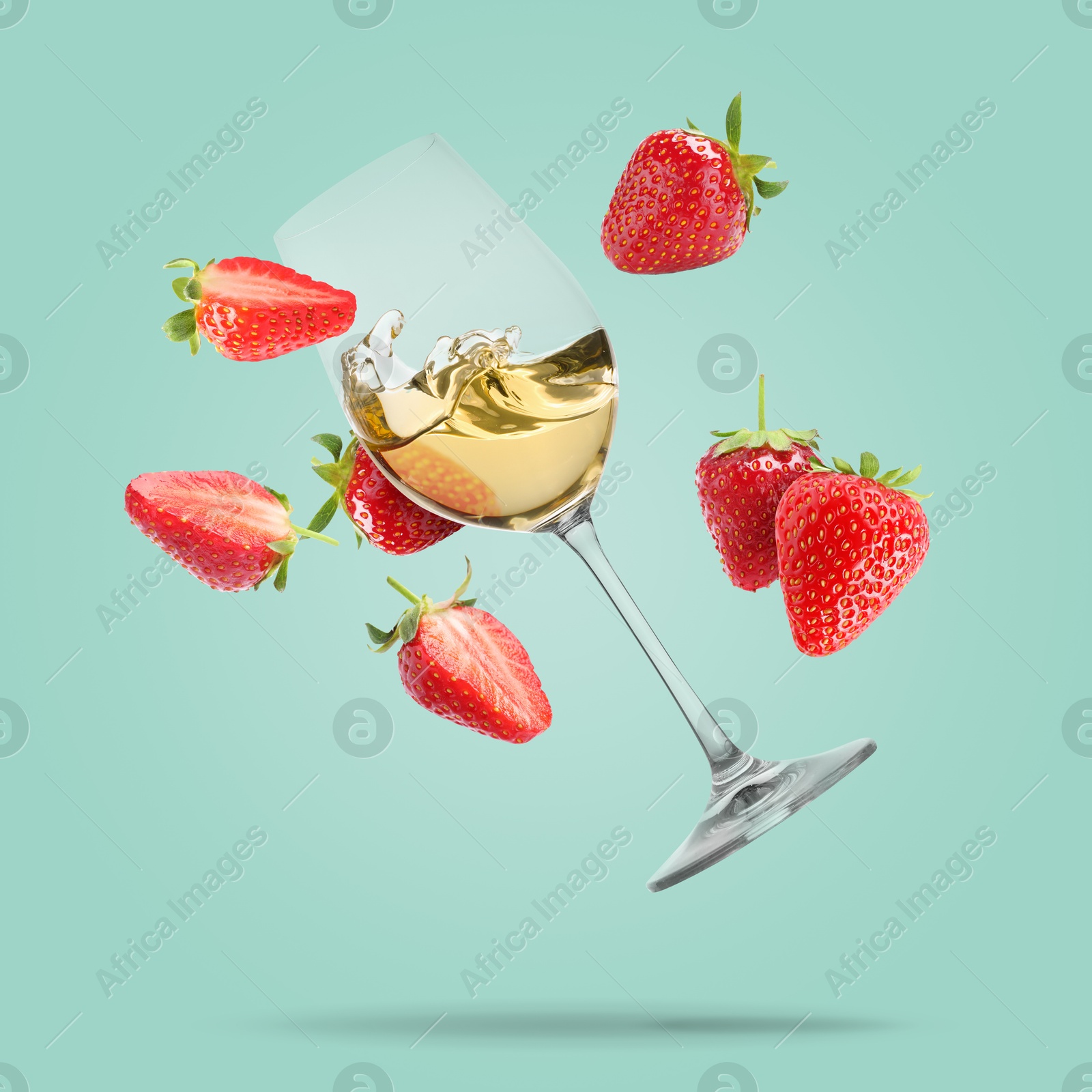 Image of Wine in glass and fresh strawberries falling against pastel turquoise background