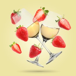 Image of Wine in glasses and fresh strawberries falling against pastel yellow background
