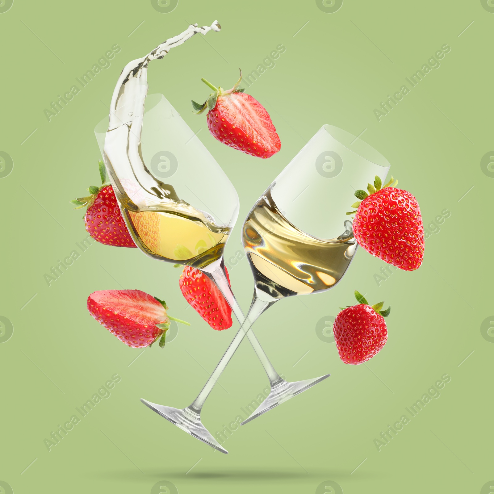 Wine in glasses and fresh strawberries falling against pastel green background Image of Wine in glasses and fresh strawberries falling against pastel green background