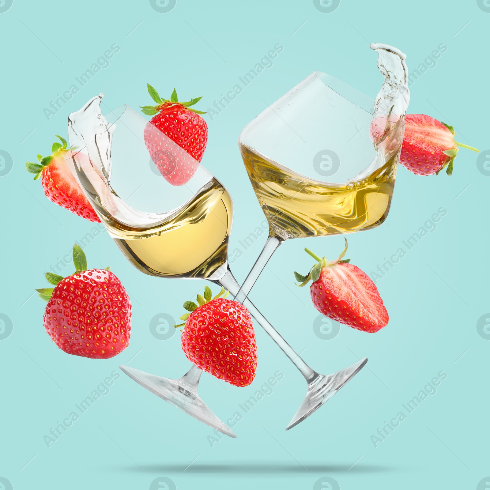 Image of Wine in glasses and fresh strawberries falling against light blue background