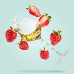 Image of Wine in glass and fresh strawberries falling against light blue background