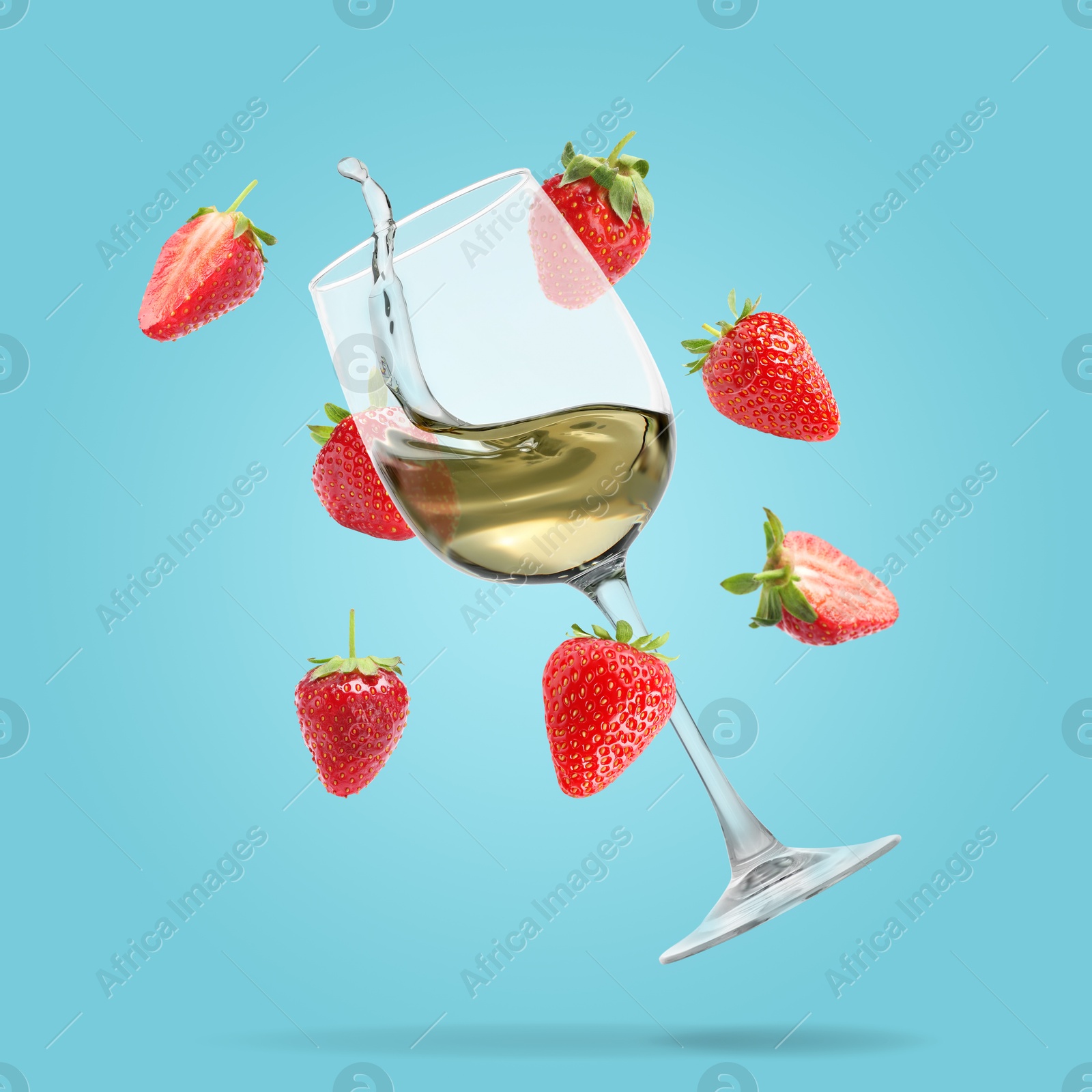 Image of Wine in glass and fresh strawberries falling against light blue background