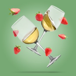 Image of Wine in glasses and fresh strawberries falling against pastel green background