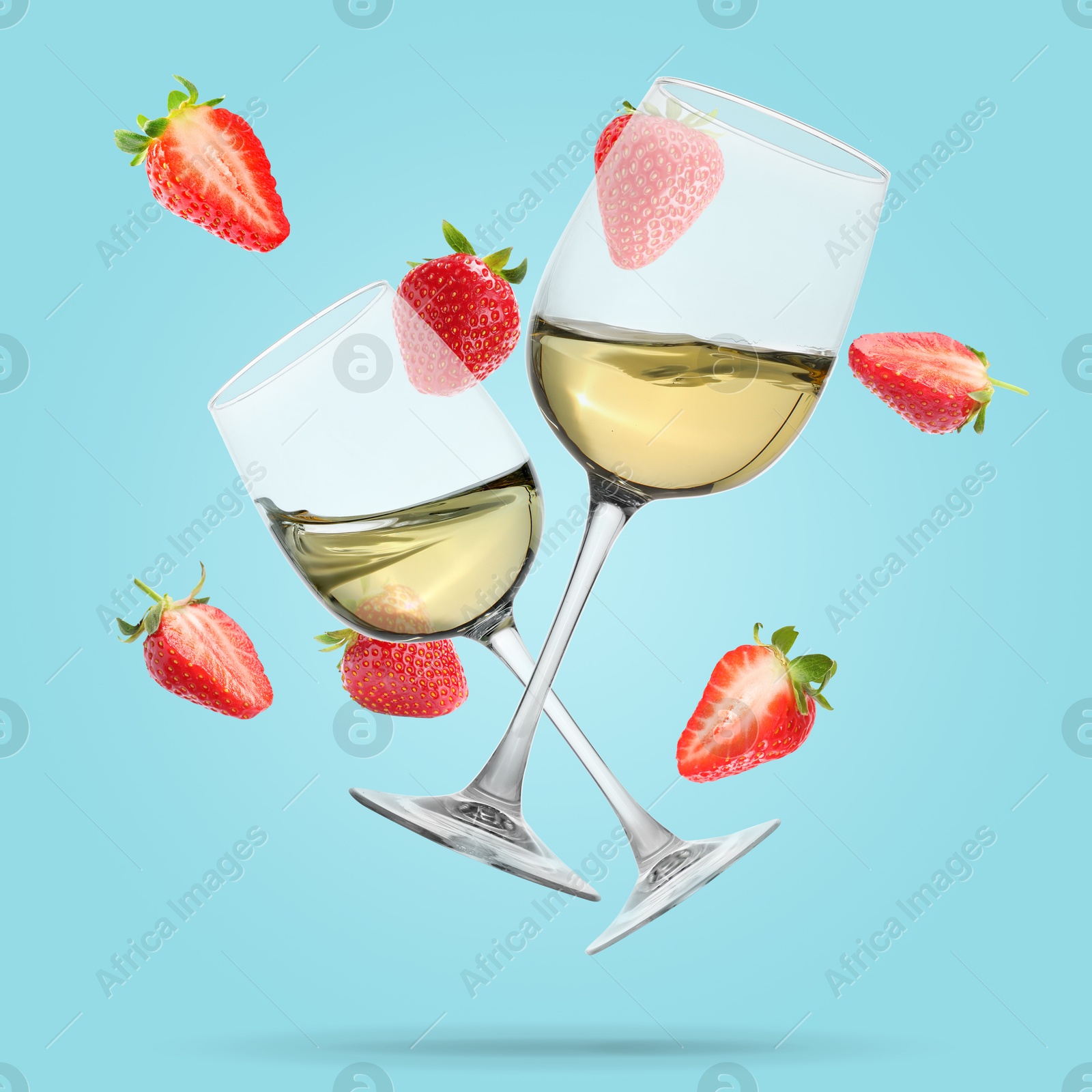 Image of Wine in glasses and fresh strawberries falling against light blue background
