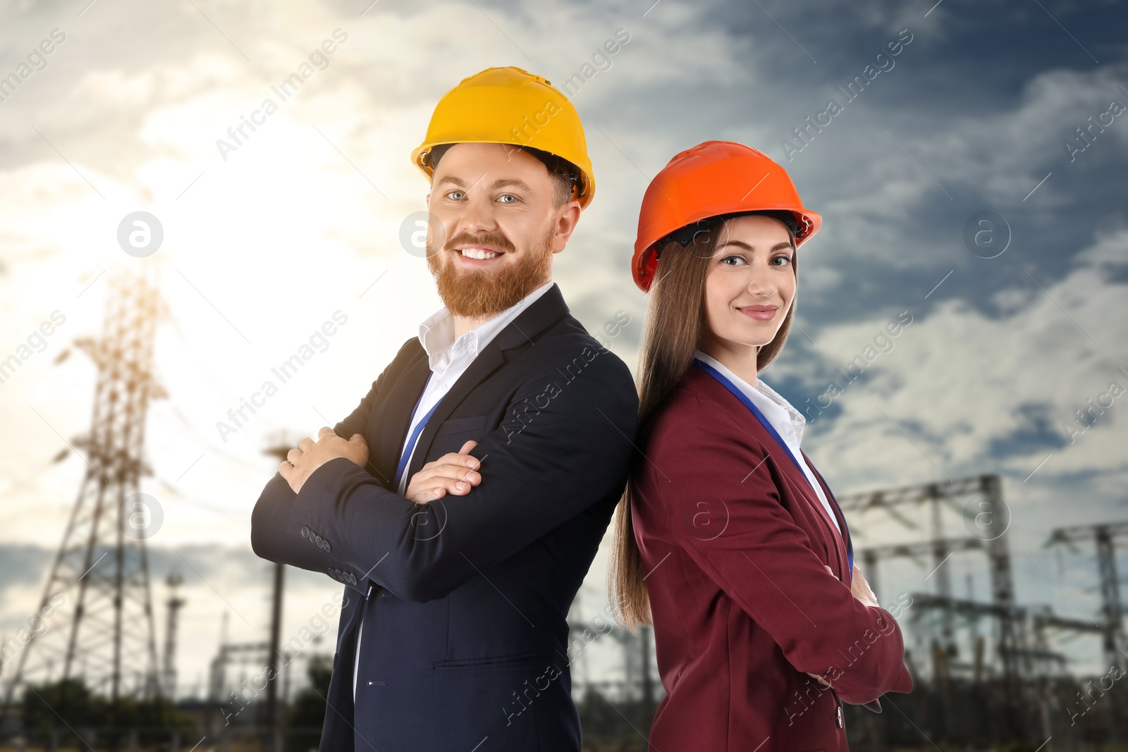 Power engineers in hard hats against electrical substation Image of Power engineers in hard hats against electrical substation