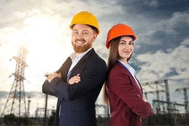 Image of Power engineers in hard hats against electrical substation