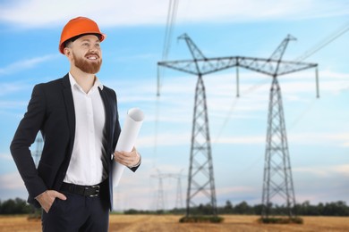 Image of Power engineer in hard hat holding draft against high voltage towers