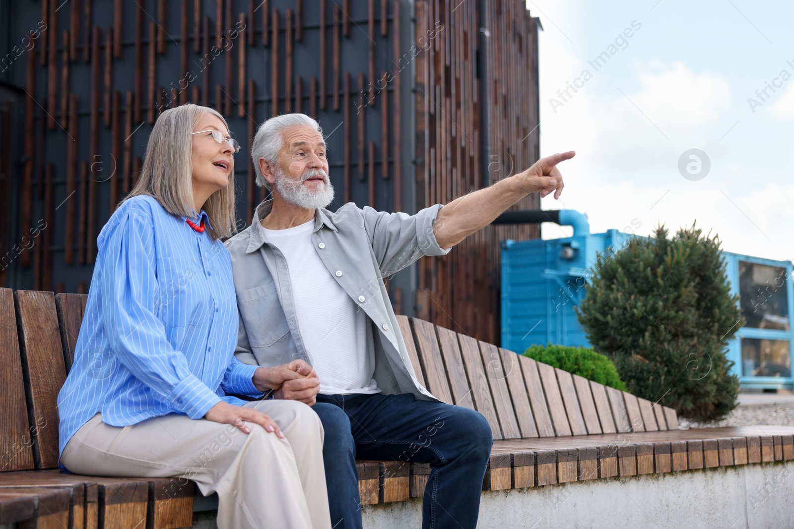 Photo of Lovely senior couple on bench near building outdoors, space for text