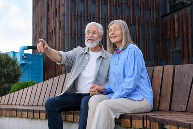 Photo of Lovely senior couple on bench near building outdoors