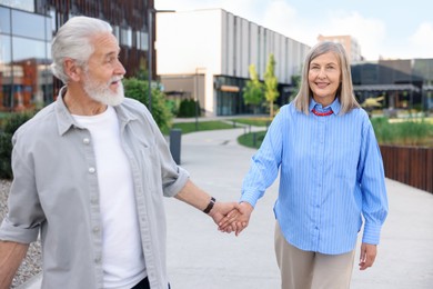 Photo of Lovely senior couple walking together on city street