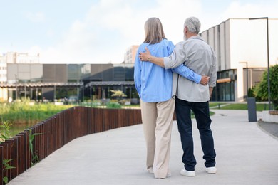 Photo of Lovely senior couple walking together on city street, back view. Space for text