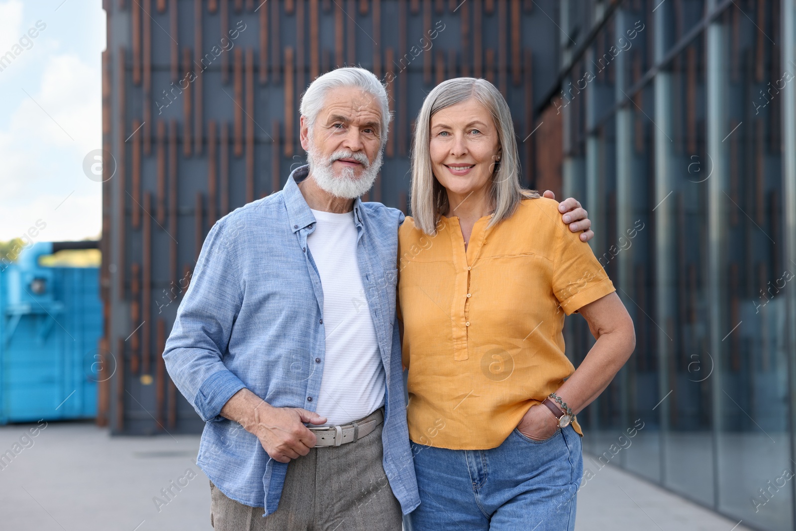Photo of Lovely senior couple walking together near building outdoors