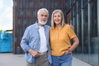 Photo of Lovely senior couple walking together near building outdoors