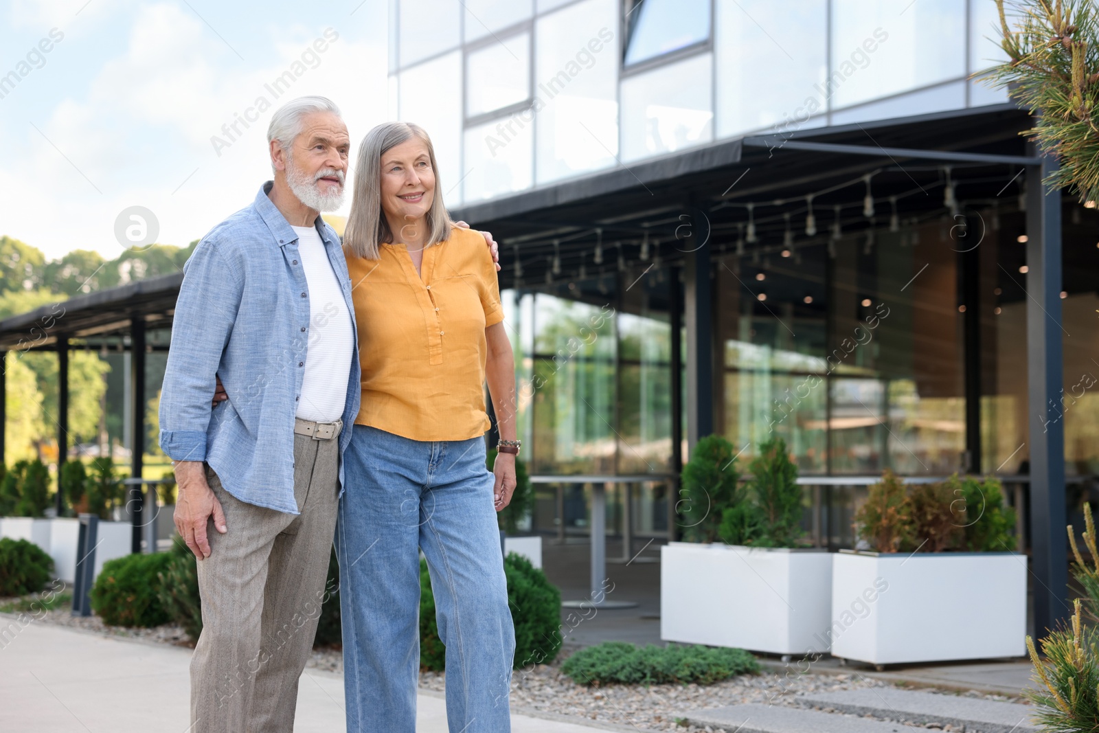 Photo of Lovely senior couple walking together near building outdoors, space for text