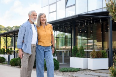 Photo of Lovely senior couple walking together near building outdoors, space for text