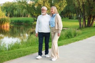 Photo of Lovely senior couple walking together near lake in park