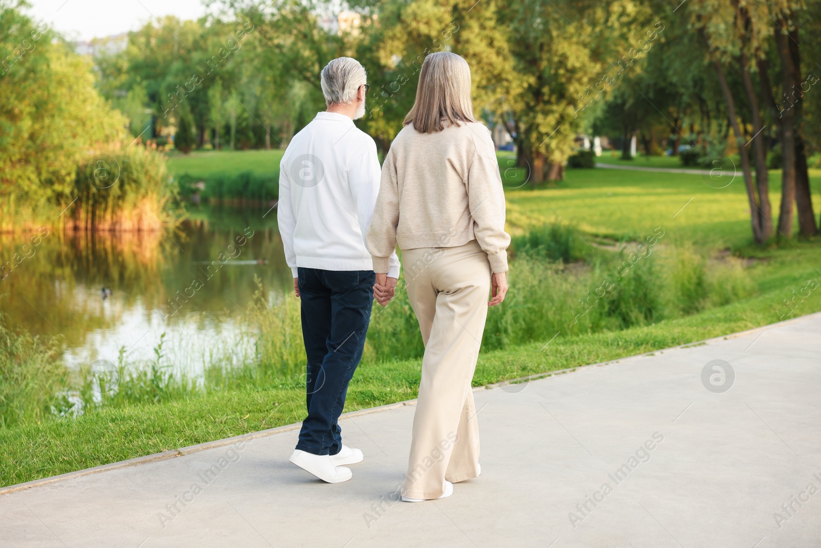 Photo of Lovely senior couple walking together near lake in park