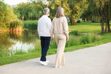 Photo of Lovely senior couple walking together near lake in park