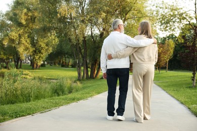 Photo of Lovely senior couple walking together in park, back view. Space for text
