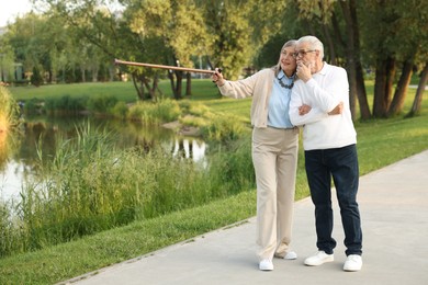 Photo of Lovely senior couple walking together near lake in park