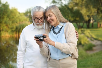Photo of Lovely senior couple with vintage photo camera in park