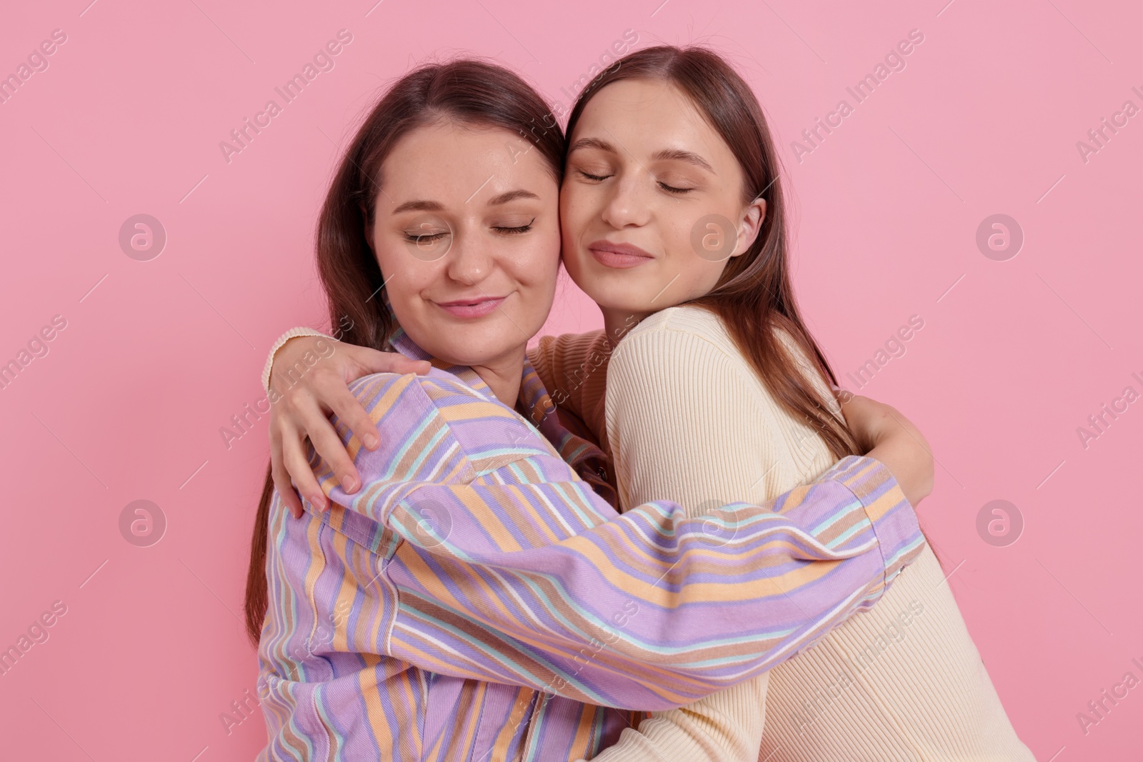 Friends hugging each other on pink background Photo of Friends hugging each other on pink background