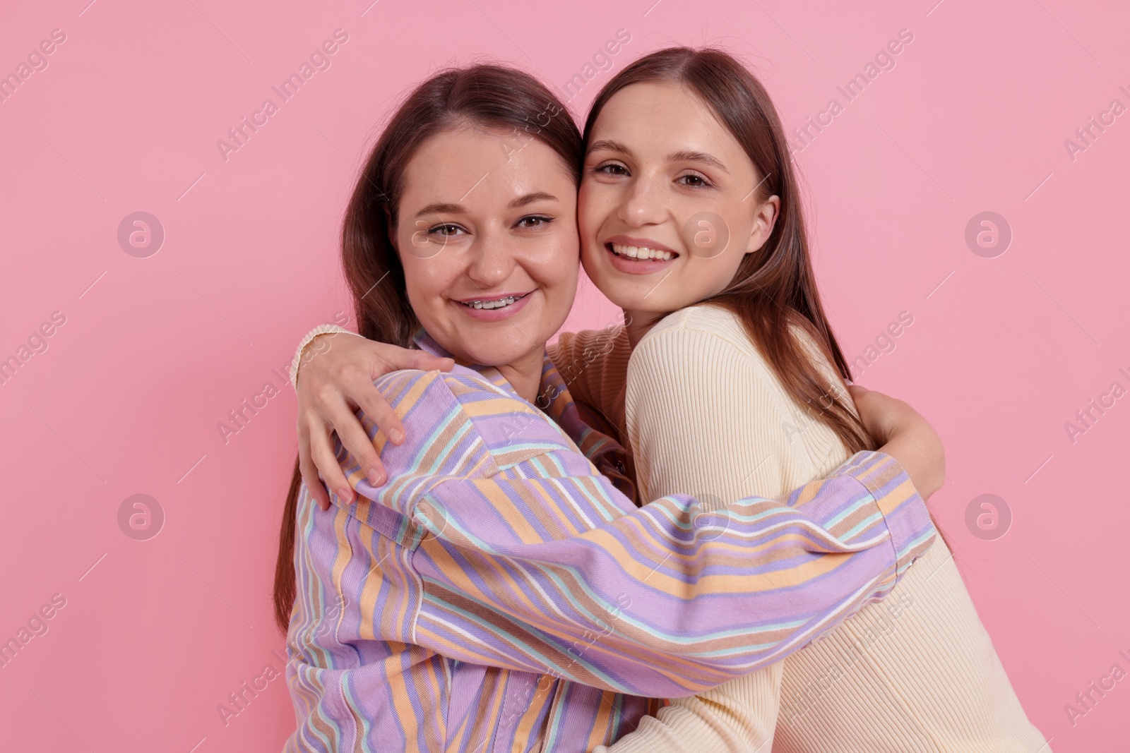 Photo of Two happy friends hugging on pink background
