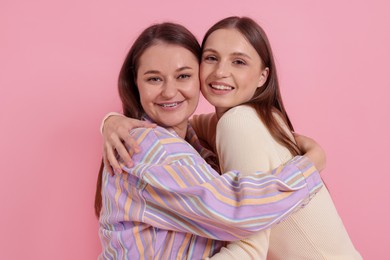 Photo of Two happy friends hugging on pink background