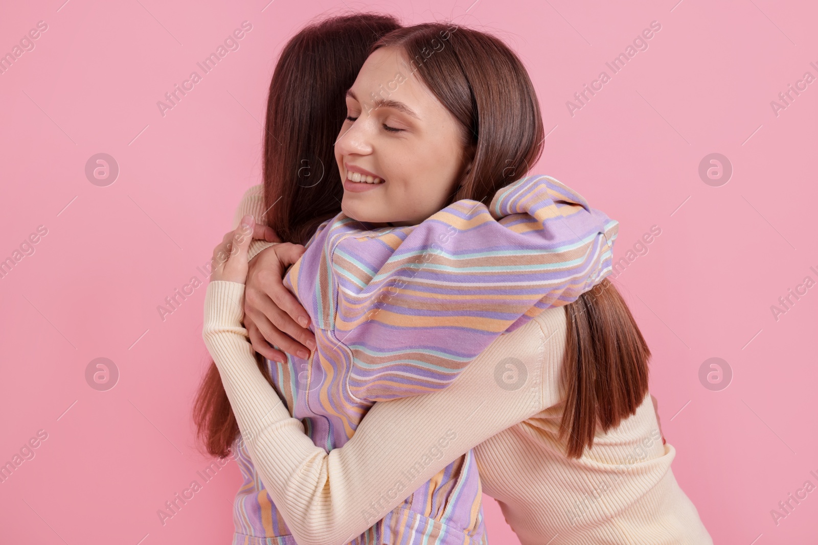 Two happy friends hugging on pink background Photo of Two happy friends hugging on pink background
