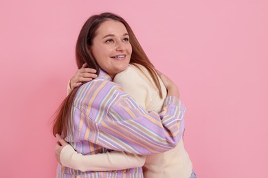 Photo of Two happy friends hugging on pink background. Space for text