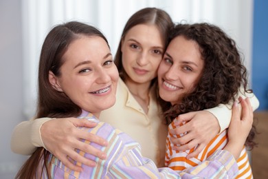Photo of Three friends hugging each other at home